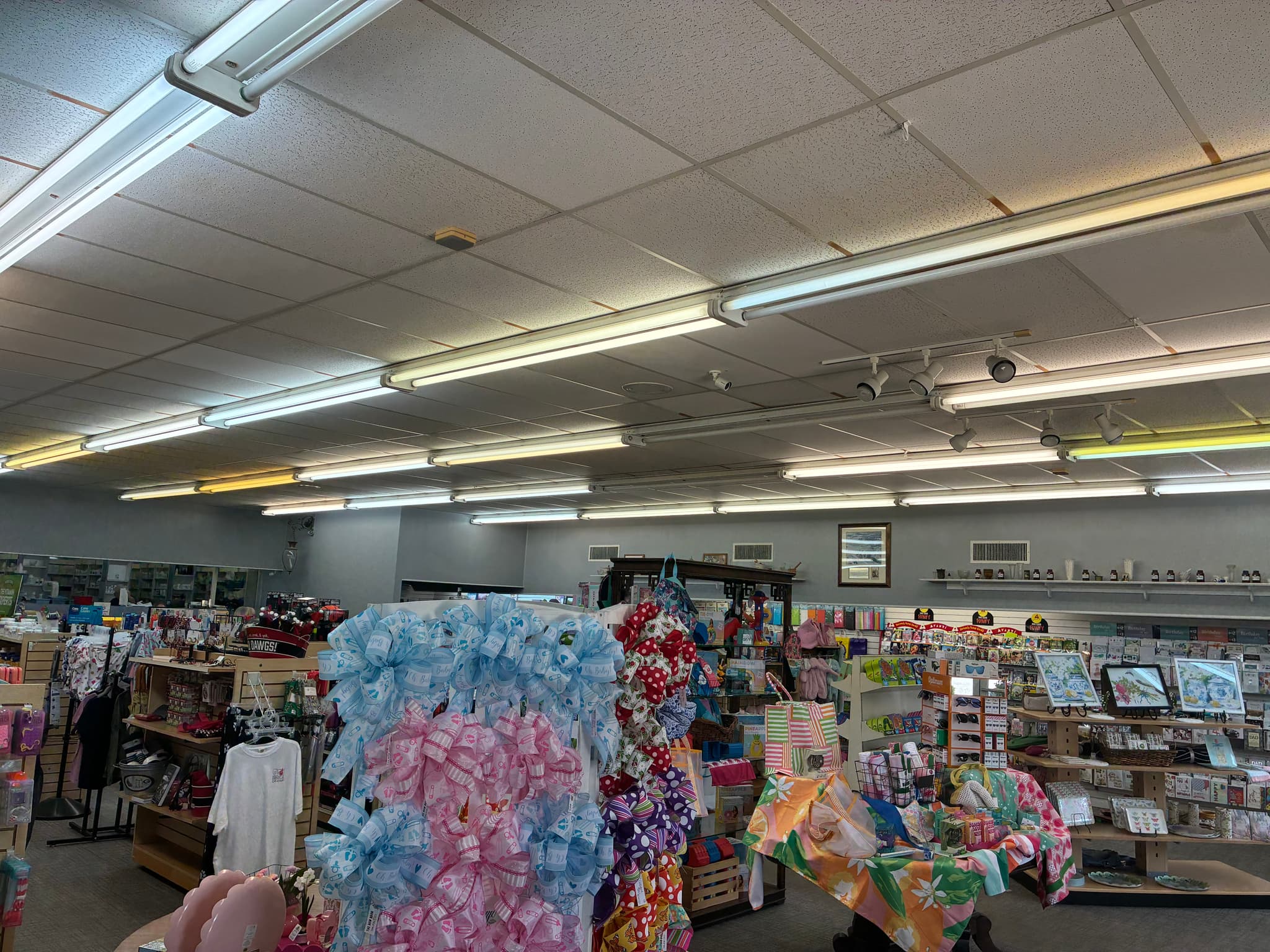Retail pharmacy with older fluorescent tube fixtures producing warm color cast and uneven light